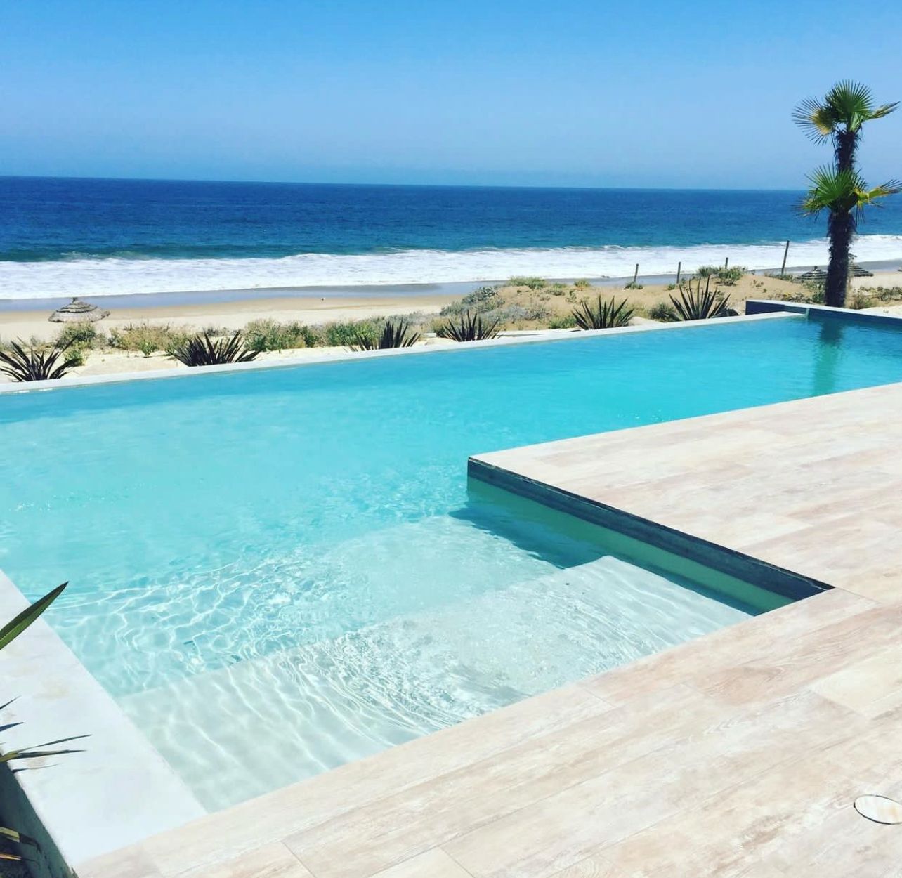 Piscina infinity frente al mar, agua turquesa cristalina y deck de piedra
