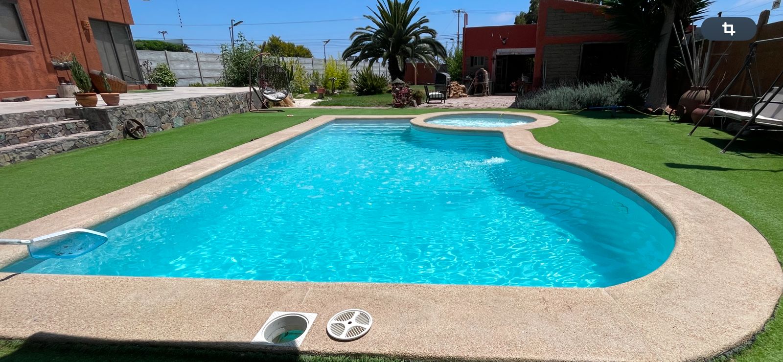 Piscina forma orgánica con jacuzzi circular integrado y jardín terminado