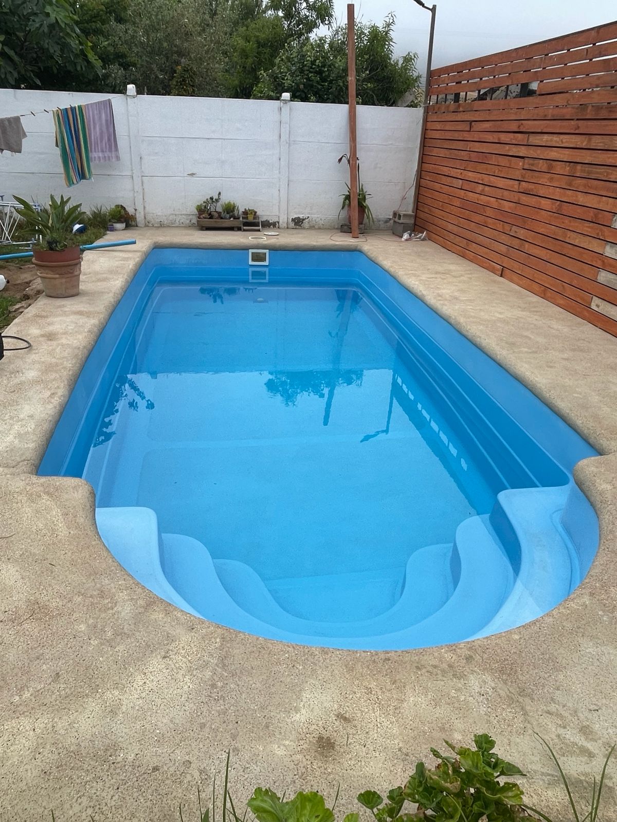 Piscina fibra de vidrio con escalones internos y cerca de madera