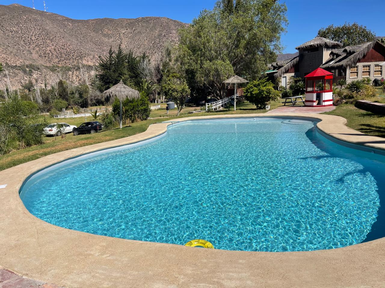 Piscina riñón terminada con agua turquesa, jardín y montañas