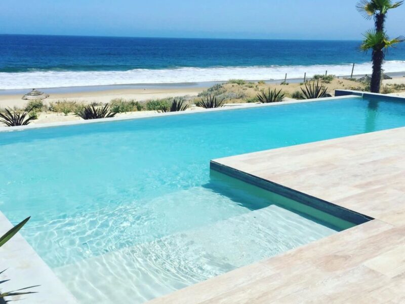 Piscina infinity frente al mar, agua turquesa cristalina y deck de piedra