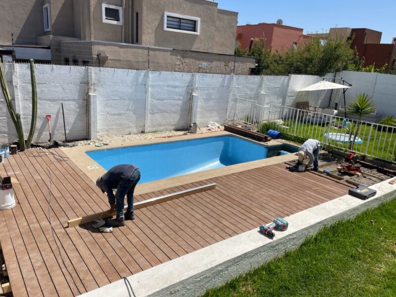 Piscina rectangular con instalación de deck de madera compuesto en proceso