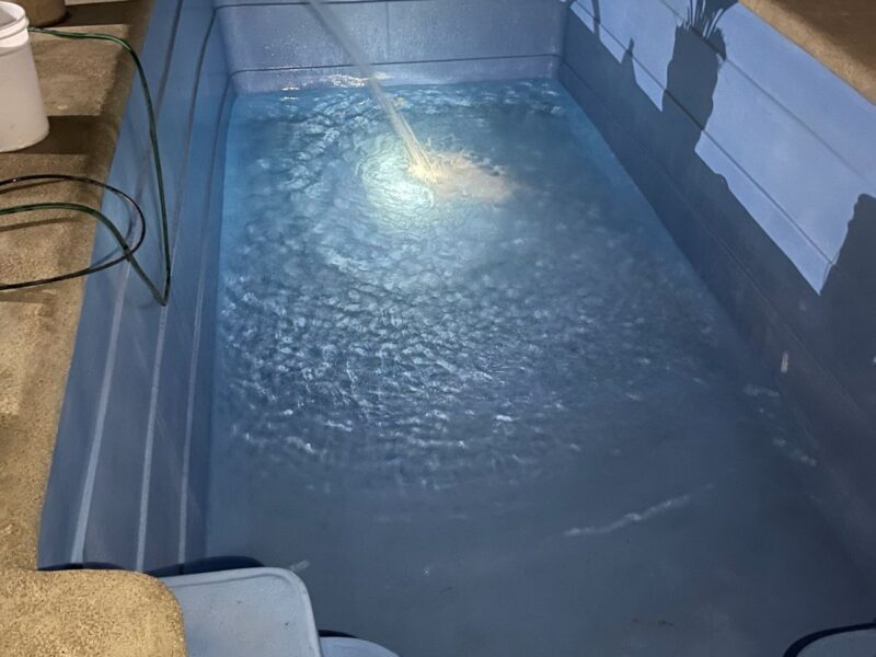 Piscina fibra de vidrio azul llenándose de noche con iluminación interior