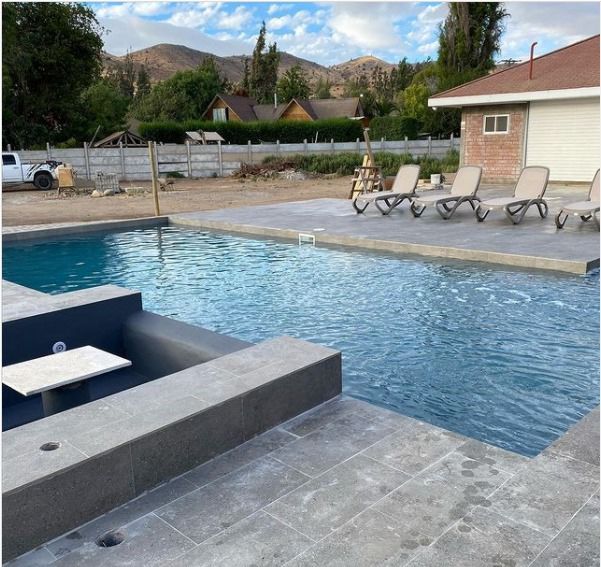 Piscina rectangular con spa de granito antracita y montañas al fondo