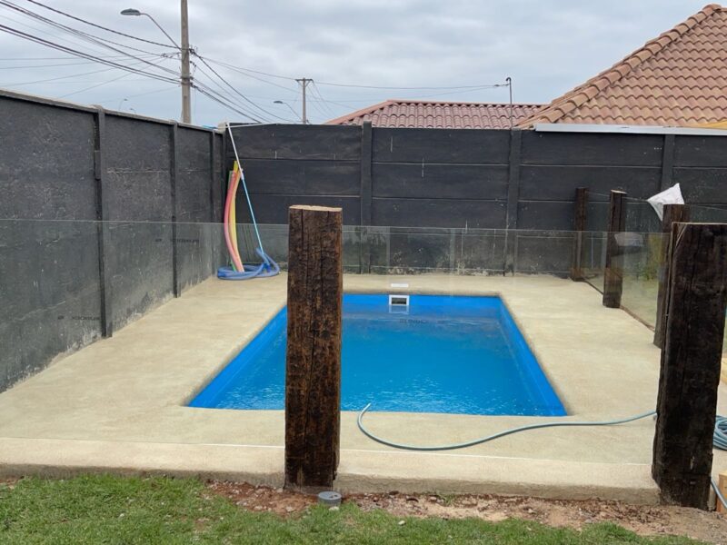 Piscina rectangular pequeña con cercado de madera rústica y vidrio templado