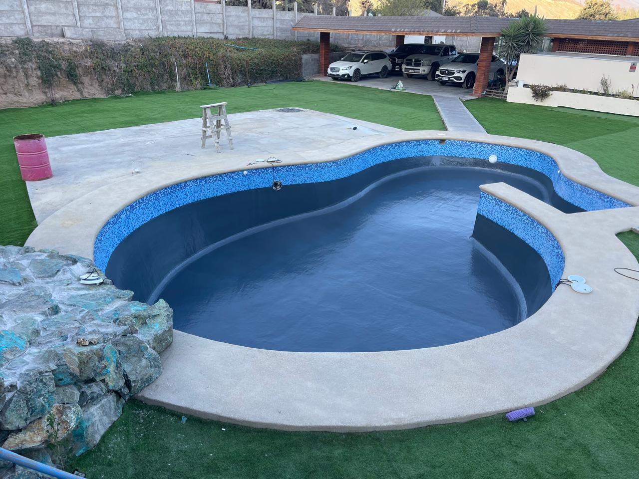 Piscina terminada con azulejo de mosaico azul y jardín verde