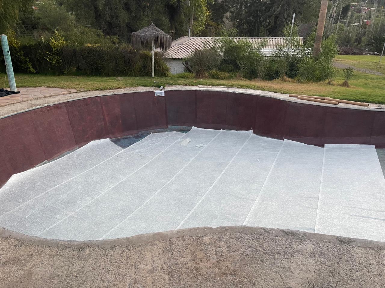 Aplicación de fibra de vidrio en el interior de una piscina en construcción